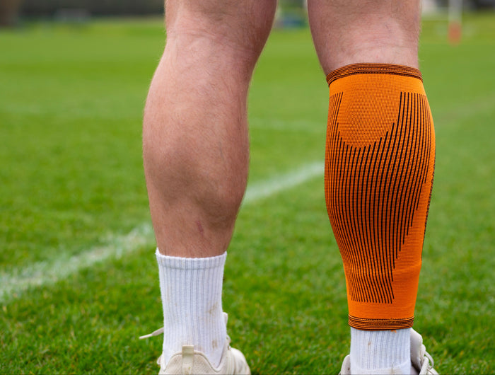 Person wearing an orange compression sleeve on a sports field